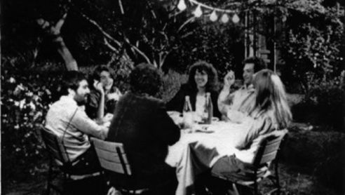 Filmstill aus TEKERLEME: Eine fröhliche Tischrunde sitzt in einem Garten.
