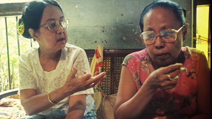 Film still from FRIENDS IN HIGH PLACES: wo women sitting next to each other talking.