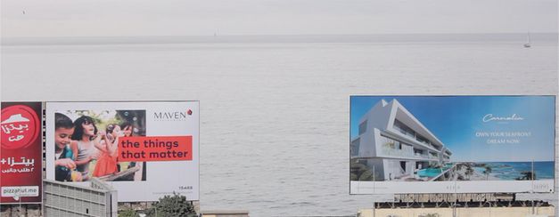 Still from the film "Gazing... Unseeing" by Mohamed Abdelkarim. Two big billboards in front of the sea.