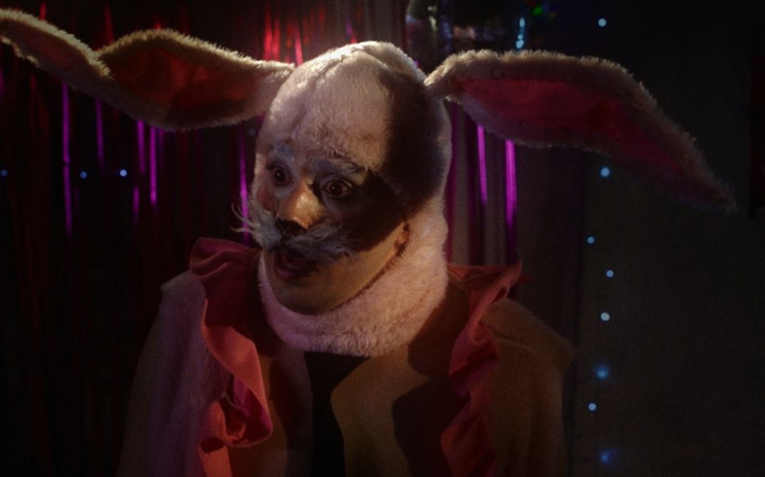 Film still from INFERNINHO: A person in a bunny costume.