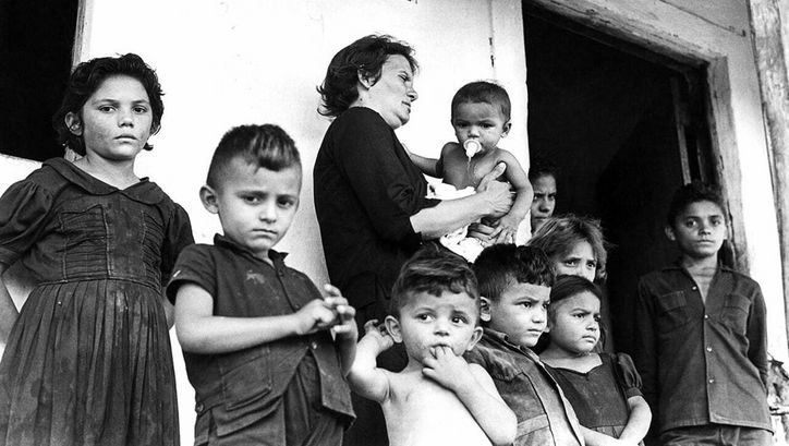 Film still from CABRA MARCADO PARA MORRER: A large family in front of a simple house.