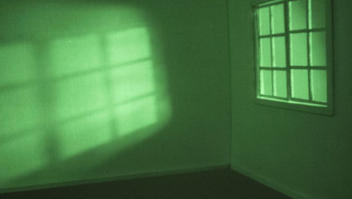 Ansicht eines leeren, in grünes Licht getauchten Zimmers.