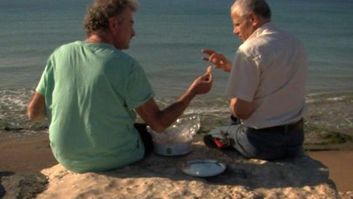 Film still from ONCE I ENTERED A GARDEN: The filmmaker sits with a friend on a rock overlooking the sea.