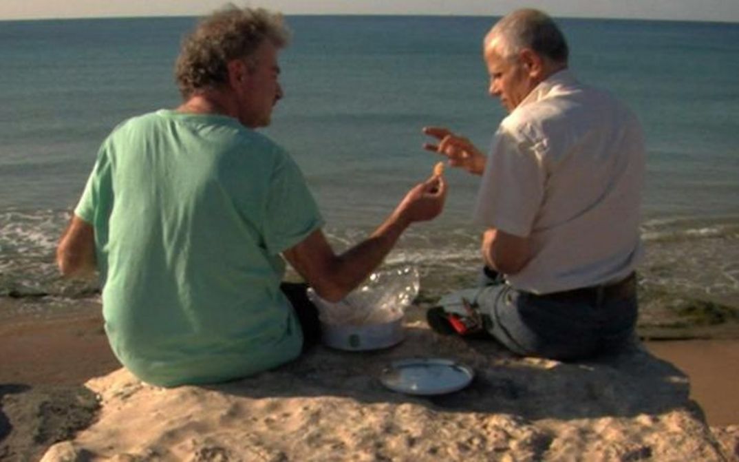 Film still from ONCE I ENTERED A GARDEN: The filmmaker sits with a friend on a rock overlooking the sea.