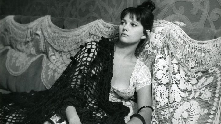 Filmstill aus LA VIACCIA: Eine Frau sitzt auf einem Sofa.