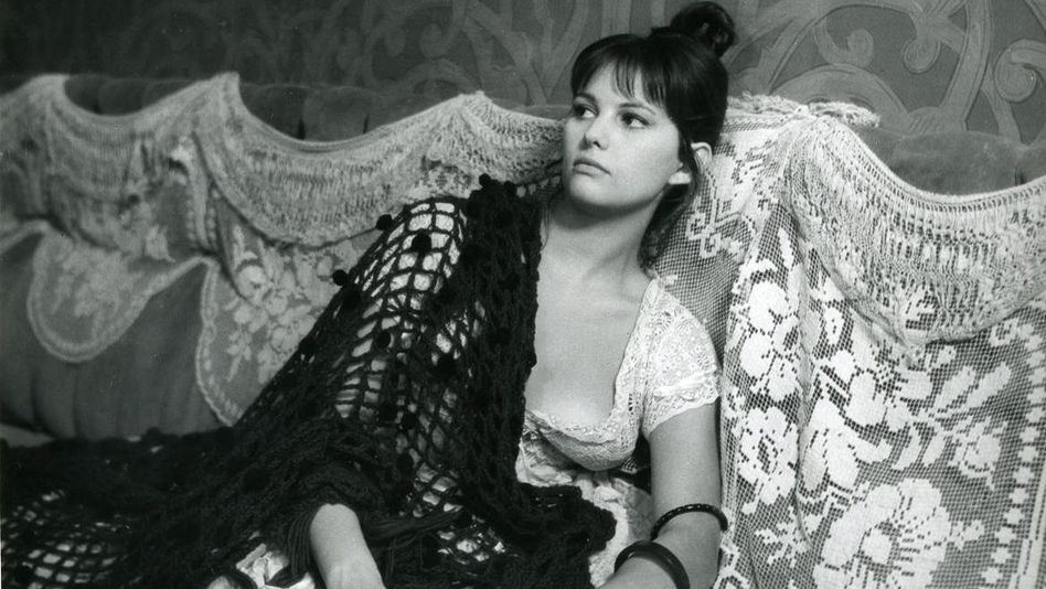 Film still from LA VIACCIA: A woman sits on a sofa.