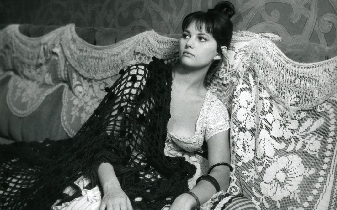 Filmstill aus LA VIACCIA: Eine Frau sitzt auf einem Sofa.