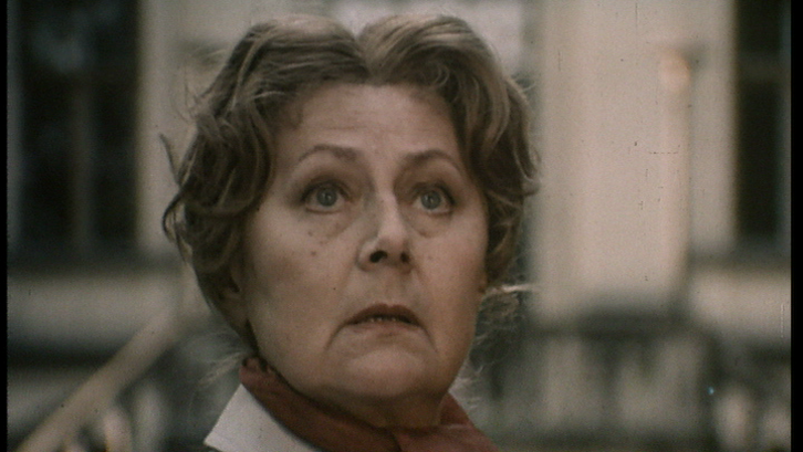 Film still from THE INVITATION: An older woman glances up.