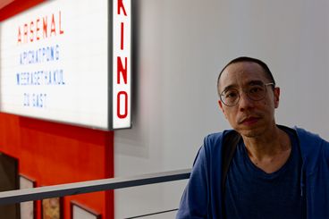 Porträt von Apichatpong Weerasethakul vor dem Leuchtkasten mit seinem Namen