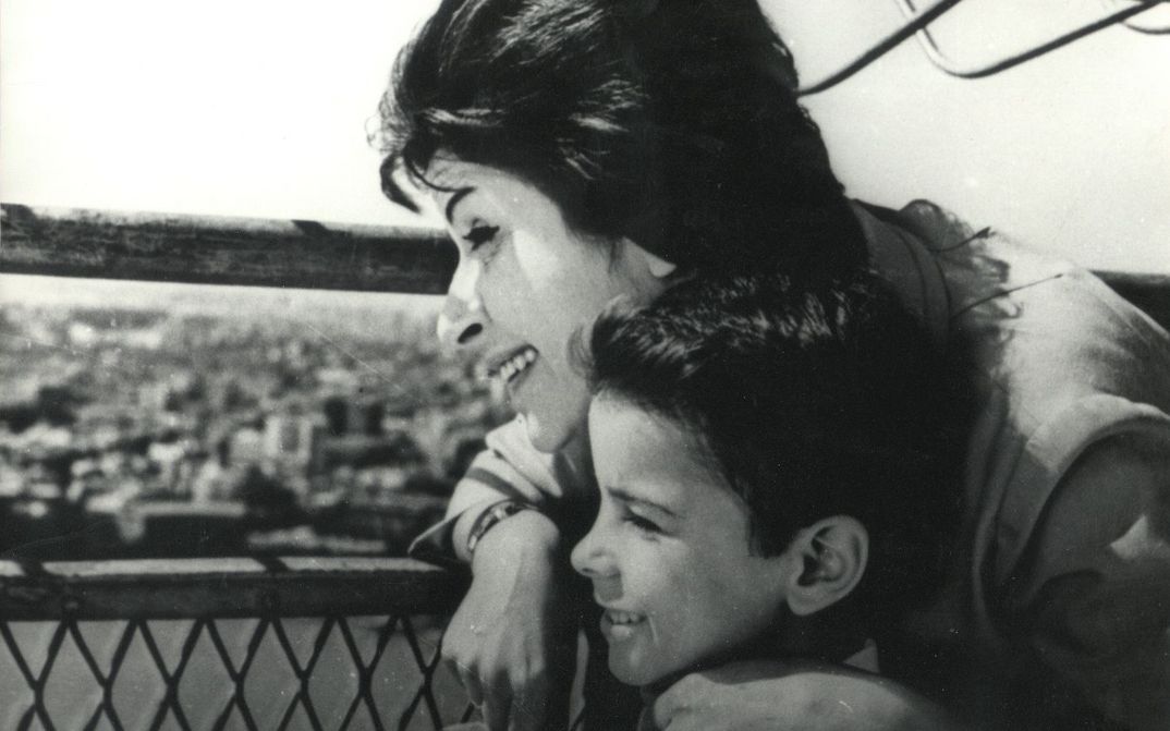 Filmstill aus DAWN OF A NEW DAY: Eine Frau und ein Junge stehen nah beieinander auf einem Dach und blicken auf die Stadt.