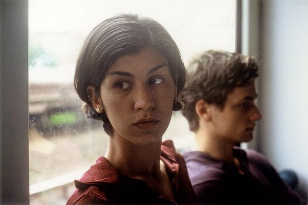 Filmstill aus „Der schöne Tag“ von Thomas Arslan. Eine junge Frau und ein junger Mann sitzen nebeneinander an einem Fenster und schauen in unterschiedliche Richtungen. 