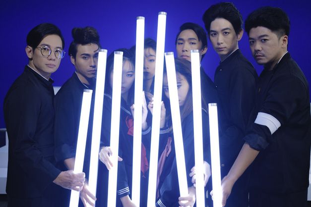 Film still from THE TRIO HALL by Su Hui-yu. The image shows a group of darkly dressed people with glow sticks. The people are looking directly into the camera. 