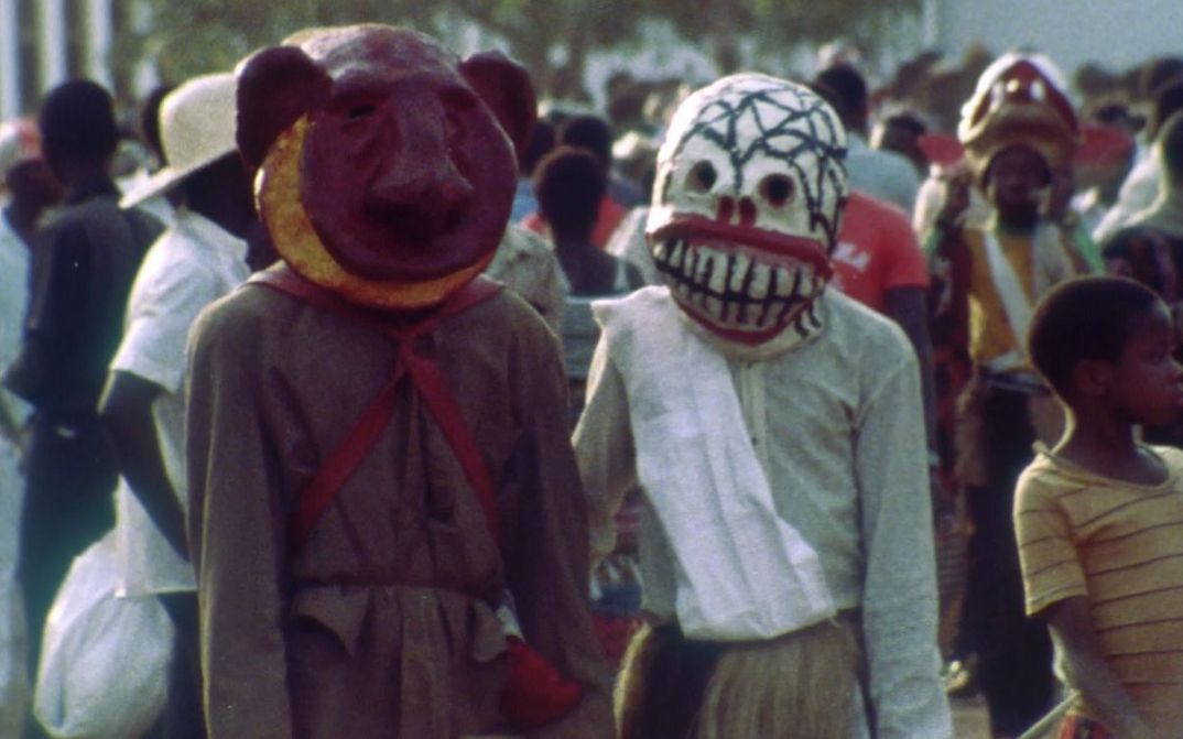 Filmstill aus XARAASI XANNE – CROSSING VOICES: Zwei Menschen in Masken inmitten einer Menschenmenge.