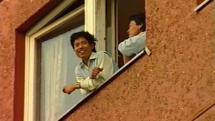 Filmstill aus BRUDERLAND: Zwei Menschen blicken aus dem geöffneten Fenster eines Hauses.