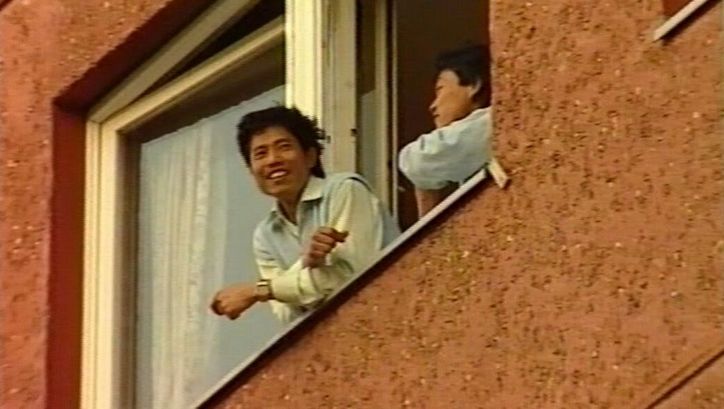 Filmstill aus BRUDERLAND: Zwei Menschen blicken aus dem geöffneten Fenster eines Hauses.