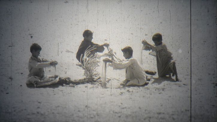 Film still from "Everyday Life in a Syrian Village": A group of children playing with sand.