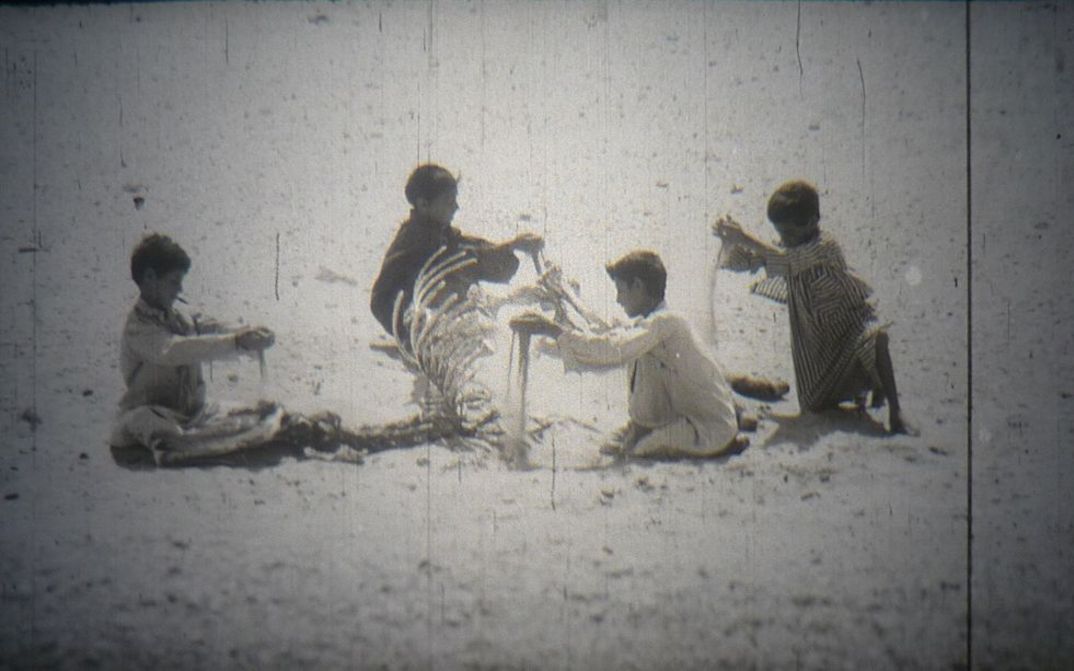 Film still from "Everyday Life in a Syrian Village": A group of children playing with sand.