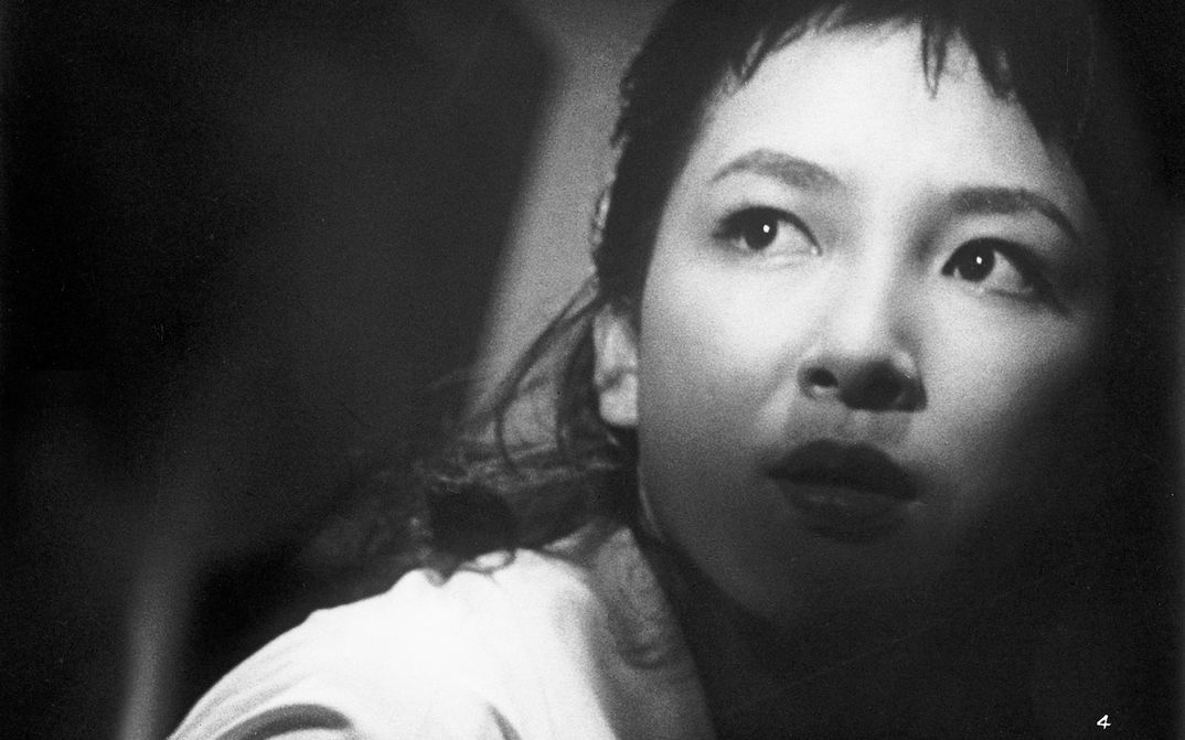Filmstill aus BLACK RIVER: Das Gesicht einer jungen Frau in Großaufnahme. Sie blickt mit erschrockenem Blick um sich. Ihr Gesicht ist halb von Schatten verdeckt.