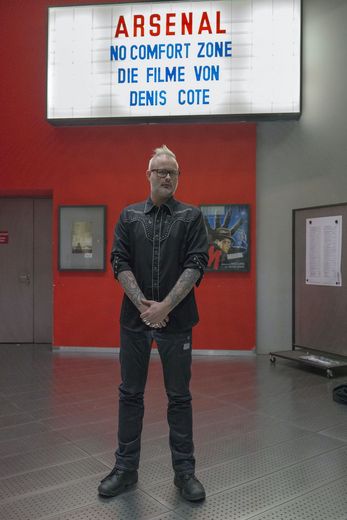 Denis Cote vor Leuchtkasten mit seinem Namen 