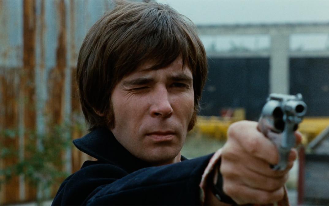 Film still from FEGEFEUER. A man aims his revolver into the distance.