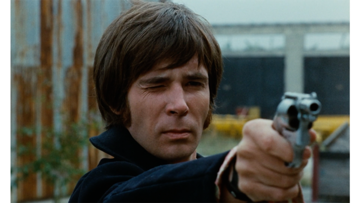 Film still from FEGEFEUER. A man aims his revolver into the distance.