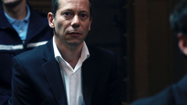 Filmstill aus LA CHAMBRE BLEUE. Ein Mann im Gerichtssaal, hinter ihm ein Polizist.