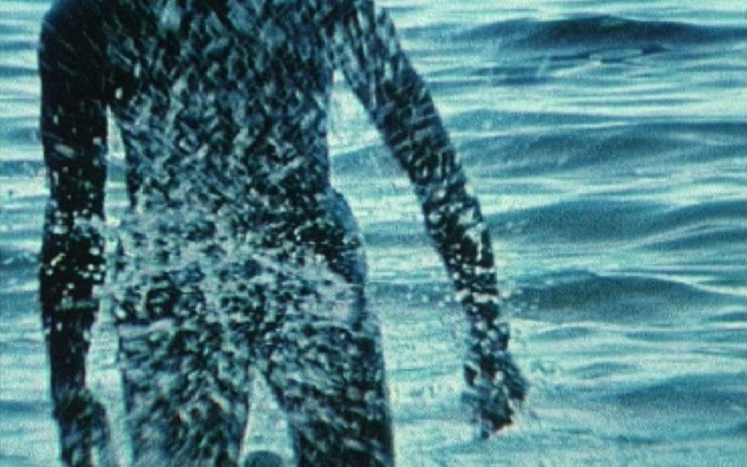 Filmstill aus BABY I WILL MAKE YOU SWEAT: Eine Person kommt aus dem Meer.