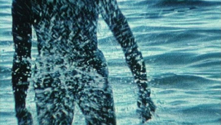 Filmstill aus BABY I WILL MAKE YOU SWEAT: Eine Person kommt aus dem Meer.