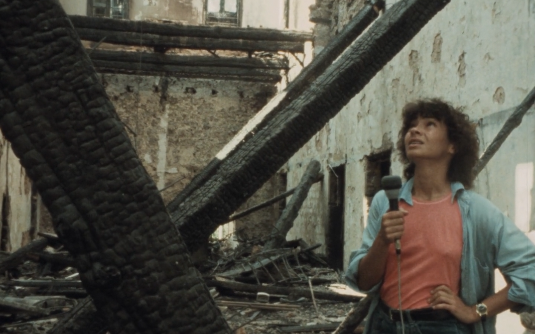 Film still from BEIRUT MY CITY: A young woman with a microphone in her hand stands in a destroyed house.