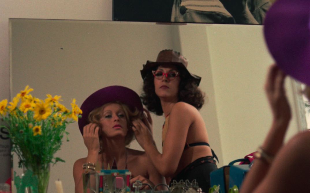 Filmstill aus THE MAN I LOVED: Zwei Frauen in Strandbekleidung und mit Hüten betrachten sich in einem Spiegel.