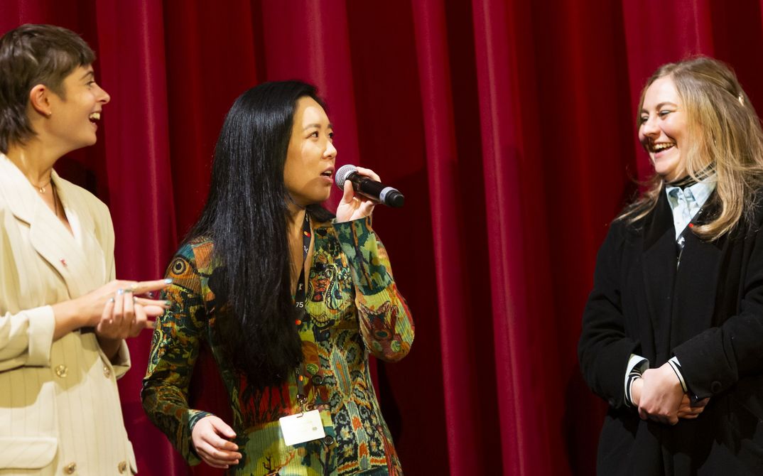Three women in front of a red curtain. 