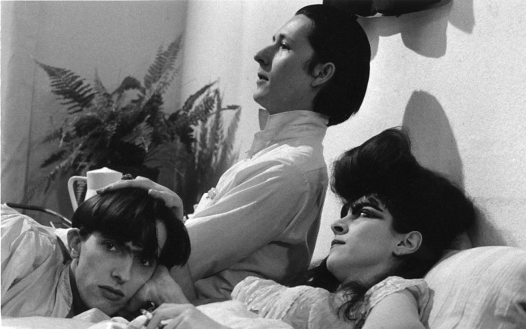 Filmstill aus TAGEDIEBE: Drei junge Menschen, zwei Männer und eine Frau mit einer auffälligen Frisur, liegen angezogen in einem Bett.