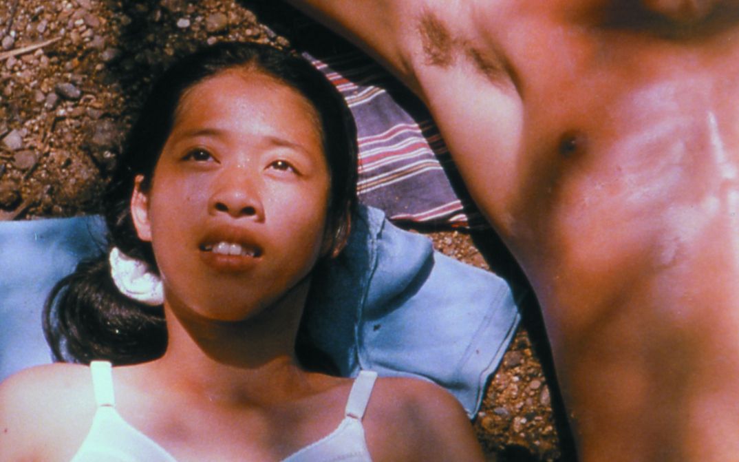 Film still from BLISSFULLY YOURS: A young woman is lying in the sun, next to her is the naked torso of a man.