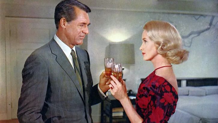 Filmstill aus NORTH BY NORTHWEST: Ein Mann und eine Frau, beide elegant gekleidet, prosten einander zu.