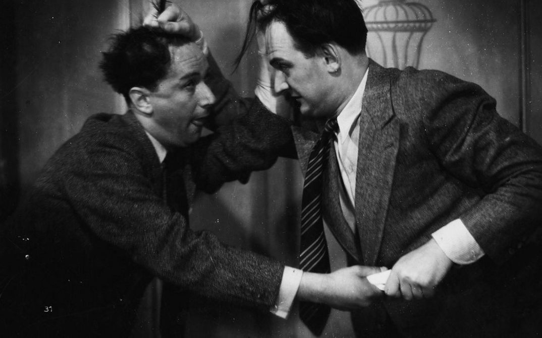 Film still from ZWEI HERZEN IM DREIVIERTEL-TAKT. Two men are wrestling with each other and grabbing each other