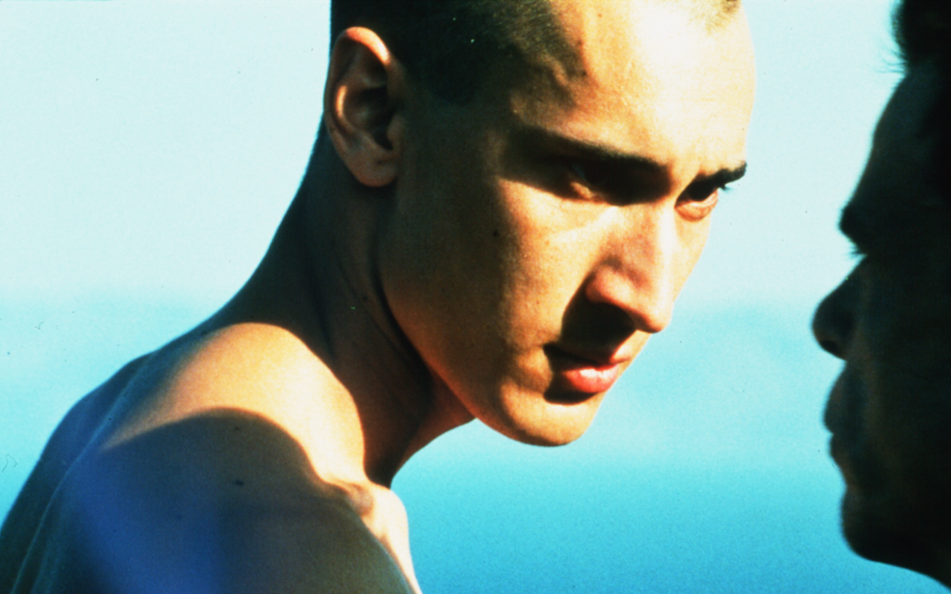 Film still from BEAU TRAVAIL: Two bare-chested men look intensely into each other