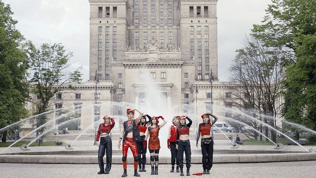 Still from the film "If Revolution Is a Sickness" by Diane Severin Nguyen. Seven people salute in front of a fountain.