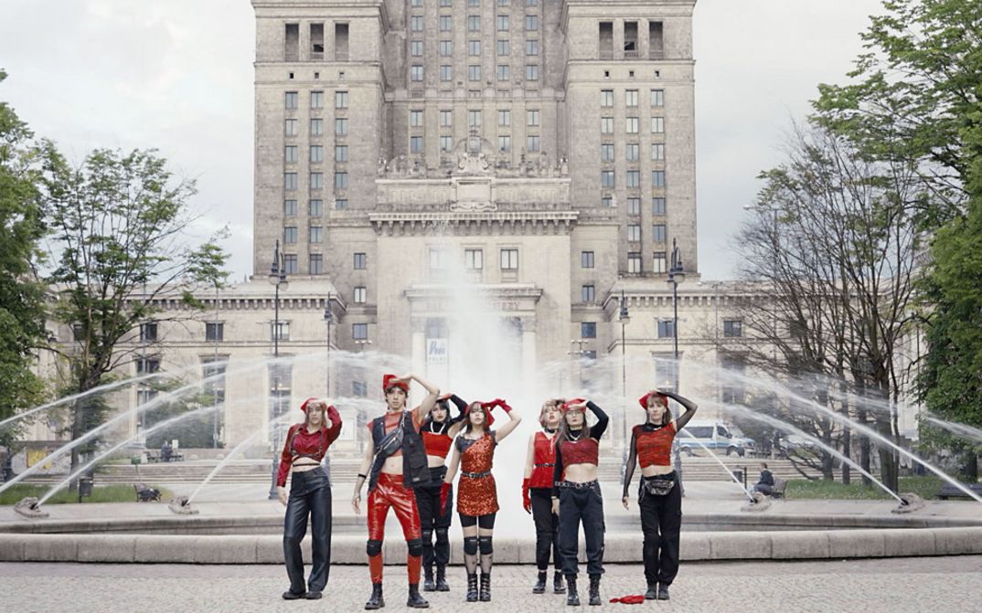 Still from the film "If Revolution Is a Sickness" by Diane Severin Nguyen. Seven people salute in front of a fountain.