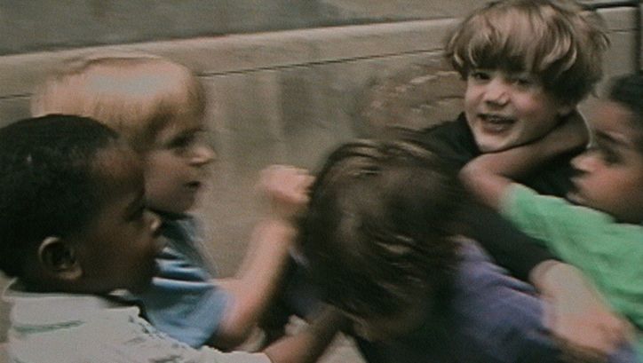 Film still from RÉCRÉATIONS: A group of children in a playful fight.