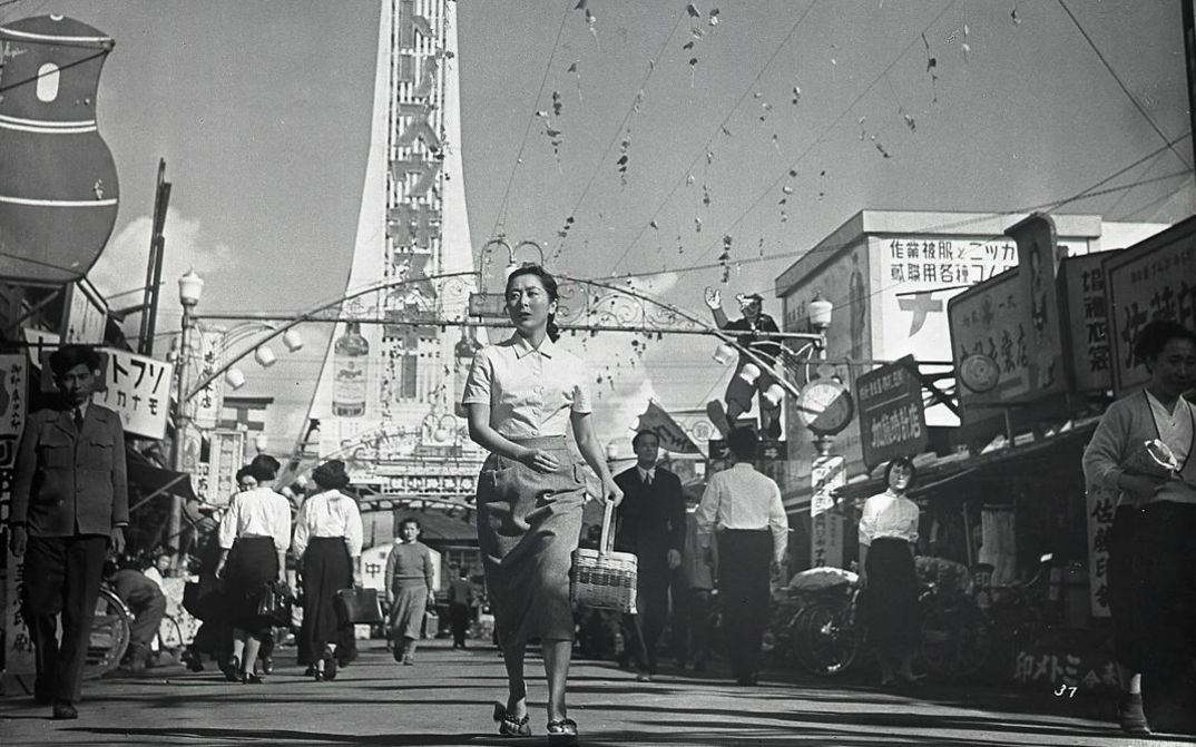 Film still from CHIBUSA YO EIEN NARE: A woman in the midst of a busy street scene.