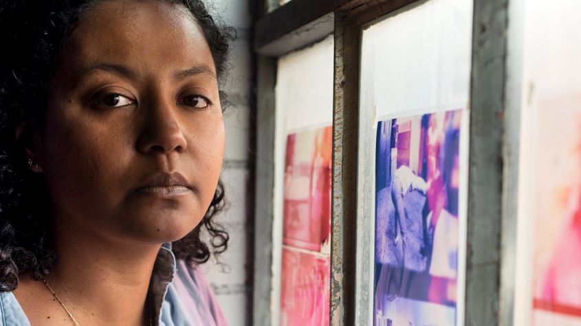 Porträt von Crystal Z Campbell neben einem buntbeklebtem Fenster stehend.