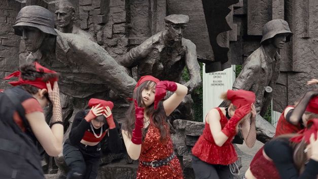 Still from the Film "If Revolution Is a Sickness" by Diane Severin Nguyen. Women dressed in red dance in front of a monument.