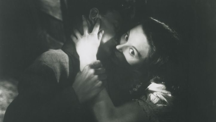 Filmstill aus DAUGHTER OF DARKNESS: Ein junges Paar in einer Umarmung. Der Hintergrund ist dunkel, das Bild hat starke Hell-Dunkel-Kontraste.