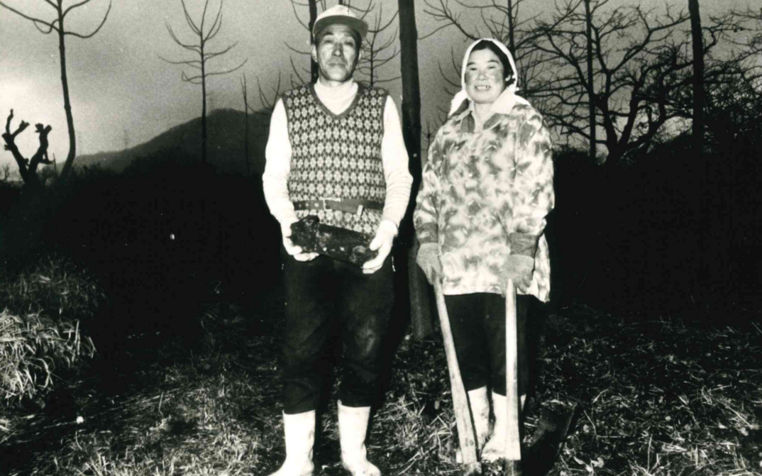Film still from THE MAGINO VILLAGE STORY: A pair of farmers is standing in the field.