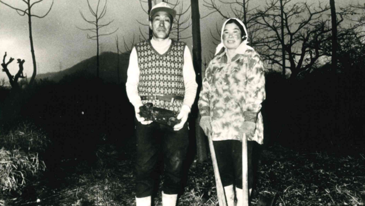 Film still from THE MAGINO VILLAGE STORY: A pair of farmers is standing in the field.
