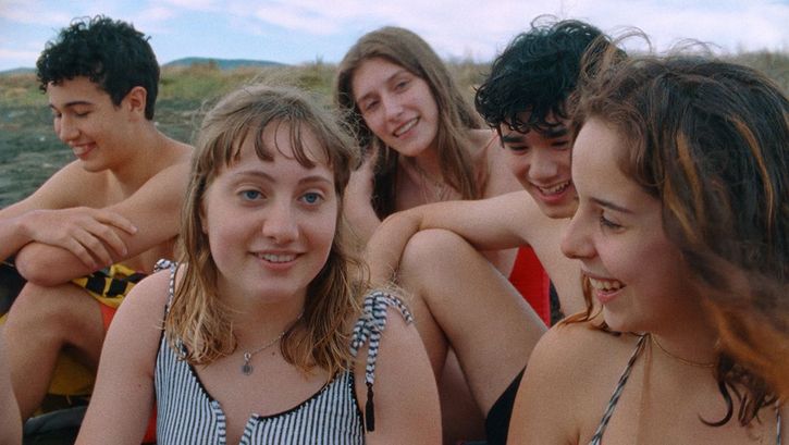 Film still from FUTURA. A group of teenagers in swimwear laugh at the camera.