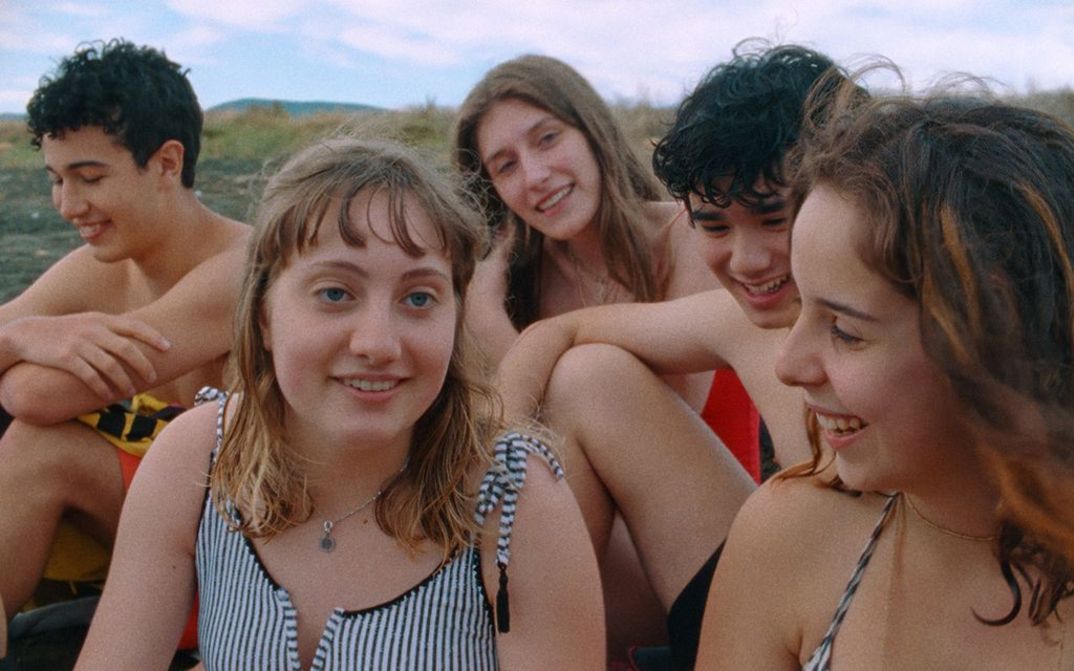 Film still from FUTURA. A group of teenagers in swimwear laugh at the camera.