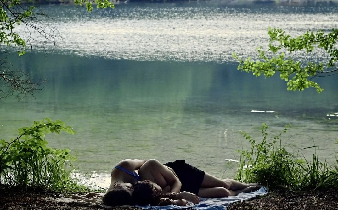 Still from the film "Afterwater" by Dane Komljen. A couple lays down in front of a lake.