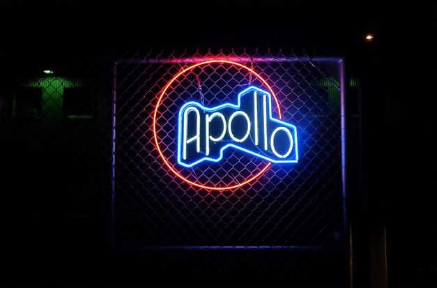 Still from the installation "The Cinema Project" by Siska. Blue and red neon lights in the darkness forming the word "Apollo".