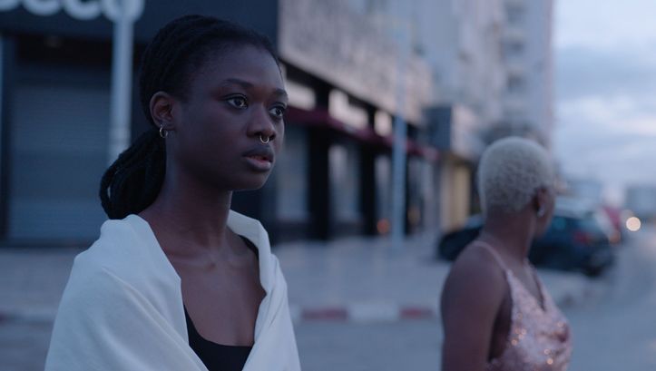 Film still from PROMIS LE CIEL: Two young women are standing on a street, the background is blurred.